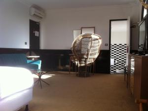 a living room with a rattan chair and a table at Hotel Ermitage in Saint-Tropez