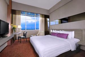 een hotelkamer met een groot bed en een groot raam bij The Alts Hotel in Palembang