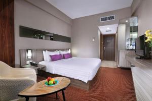 een hotelkamer met een bed en een woonkamer bij The Alts Hotel in Palembang