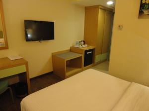 a hotel room with a bed and a tv on the wall at The Pavilion Hotel in Sandakan