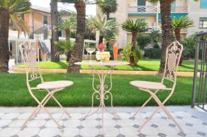 two chairs and a table in a courtyard with palm trees at Mediterraneo Emotional Hotel & Spa in Santa Margherita Ligure