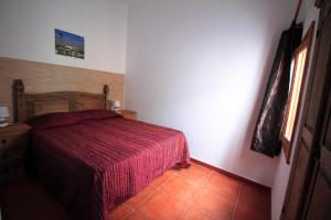 a bedroom with a bed with a red bedspread and a window at MONTAÑA VALLES DE ORTEGA -D in Antigua