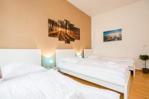 two beds in a room with white sheets at Work & stay apartments DD in Düsseldorf