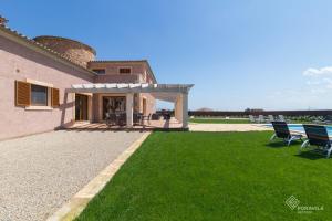 an external view of a house with chairs on the grass at Moli den Sion in Sa Pobla