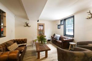 a living room with leather couches and a table at Feathertop Alpine Lodge in Falls Creek