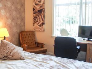 a bedroom with a bed and a desk and a chair at Leaded Light Guest House in Solihull