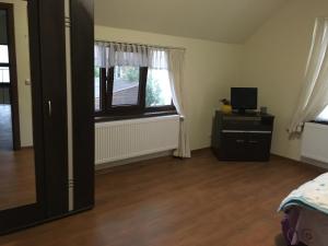 a room with a bed and a television and two windows at Casa in zona linistita, Campia Turzii in Cîmpia Turzii