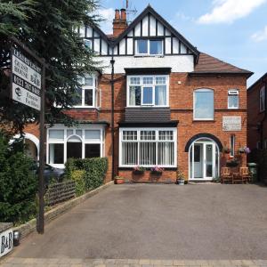 a large brick house with a driveway in front of it at Leaded Light Guest House in Solihull