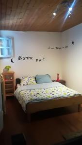 ein Schlafzimmer mit einem Bett mit einem Schild an der Wand in der Unterkunft Gîte de Lolotte et Gégé in Audeux
