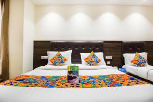 Habitación de hotel con 2 camas y almohadas coloridas en FabExpress Le Continental en Nueva Delhi
