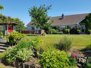 een huis met een tuin met bloemen en planten bij Meadow View B&B in Ballymena