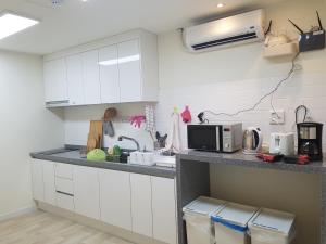 a kitchen with white cabinets and a counter with a microwave at Seoul Forest Stay in Seoul