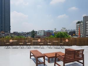 eine Terrasse mit 2 Bänken und Stühlen sowie einem Tisch in der Unterkunft Seoul Forest Stay in Seoul