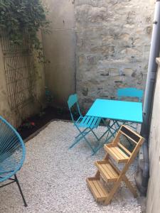 a blue table and chairs next to a stone wall at F2 cosy avec Cour in Milly-la-Forêt