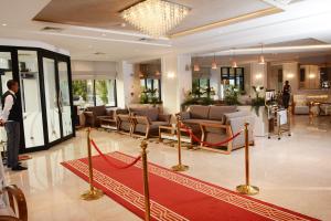 un homme debout dans un hall avec un tapis rouge dans l'établissement Marigold Hotel, à Tunis