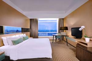 a hotel room with a large bed and a television at The Alts Hotel in Palembang