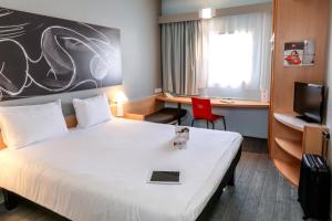 オランジュにあるイビス オランジュ シュッドの大きなベッドと赤い椅子が備わるホテルルームです。