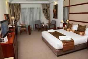 チュニスにあるMarigold Hotelの大型ベッドとテレビが備わるホテルルームです。