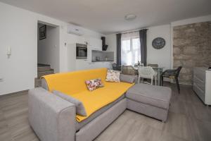 sala de estar con sofá y manta amarilla en Apartmani Sliško, en Novalja