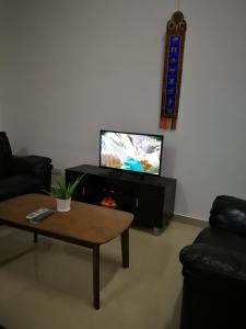 sala de estar con mesa de centro y TV de pantalla plana en Happy Holiday home, en Balik Pulau