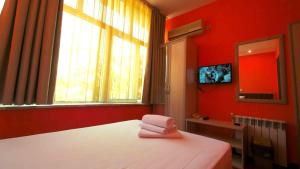 1 Schlafzimmer mit roten Wänden und 1 Bett mit 2 Handtüchern in der Unterkunft Hotel Alabin Central in Sofia