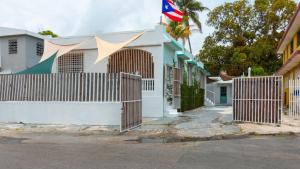 a white house with a fence and a flag at Calle Hollanda 1 Bedroom Home in San Juan