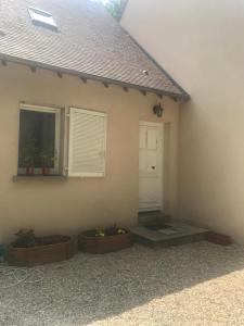 Noisy-sur-École的住宿－楓丹白露溫馨度假屋，门旁有两株盆栽植物的房子