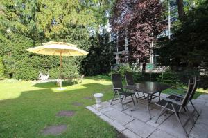 a picnic table with a umbrella on a lawn at Hotel Leopold in Munich
