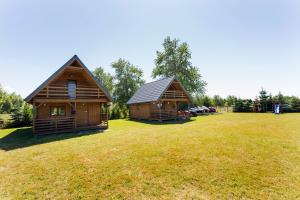 two log homes in a field with a playground at U Marleny in Ustka