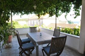 een houten tafel en stoelen op een patio met uitzicht bij Pinta Apartments in Lumbarda