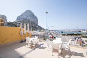 a balcony with white tables and chairs and a mountain at Hotel Porto Calpe in Calpe