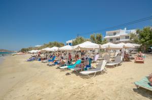 a group of people sitting on a beach with umbrellas at Naxos Hostel in Agia Anna Naxos