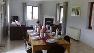 a dining room table with chairs and a long table with plates at Ardnagashel Woods in Bantry