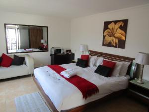 Buckleigh Guesthouse في ديربان: غرفة نوم بسرير كبير ومخدات حمراء وبيضاء