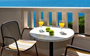 a table with two glasses of juice and pears on a balcony at Apartmani Lučica in Mimice