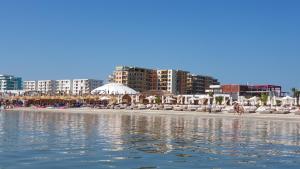 a beach with chairs and buildings and the water at De Silva Residence in Mamaia