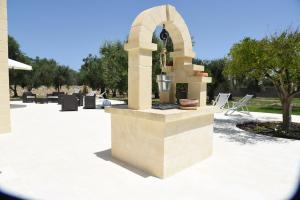 a stone fountain in a courtyard with chairs and trees at Tenuta Buonasorte in Torre dell'Orso