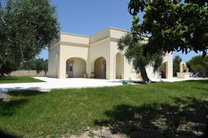a large white building with a tree in the foreground at Tenuta Buonasorte in Torre dell'Orso