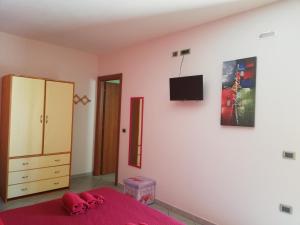 1 dormitorio con 1 cama y TV en la pared en Entula, en Tortolì