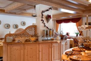 a kitchen with wooden cabinets and a table with dishes at Alpenhotel Panorama in Campitello di Fassa