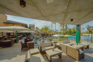 a restaurant with tables and chairs and a pool at PortBlue Club Pollentia Resort & Spa in Alcudia