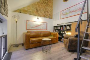 a living room with a brown leather couch and chairs at Academy's Loft in Dijon