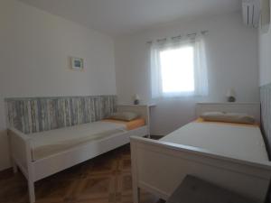 two beds in a white room with a window at Apartments Pegla in Nerezine