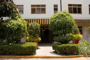 un edificio con árboles y arbustos frente a un edificio en HOTEL ESTADIO S.A, en Ciudad de México