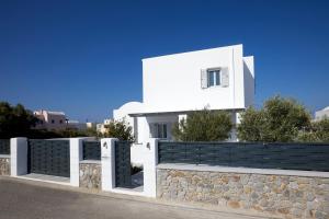 een wit huis met een stenen hek bij Tramonto Private Villa in Monolithos