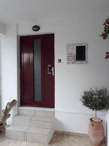 a red door on a white wall with a plant at Limanaki Ss View Apartment in Kavala