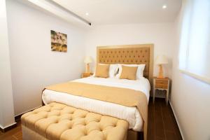 a bedroom with a large bed with a tufted foot board at Salonikiou Beach Apartments & Villas in Ayios Nikolaos Sithonia +134 photos