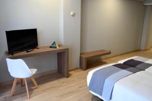 a bedroom with a bed and a desk with a television at Hotel Alda Sada Marina in Sada