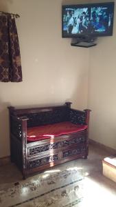 フェズにあるリヤド レッチーナの木製ベンチ付きの客室で、壁にテレビが備わります。