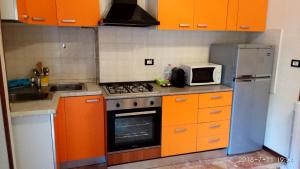 eine Küche mit Orangenschränken, einem Herd und einer Mikrowelle in der Unterkunft Bixio in Pavia